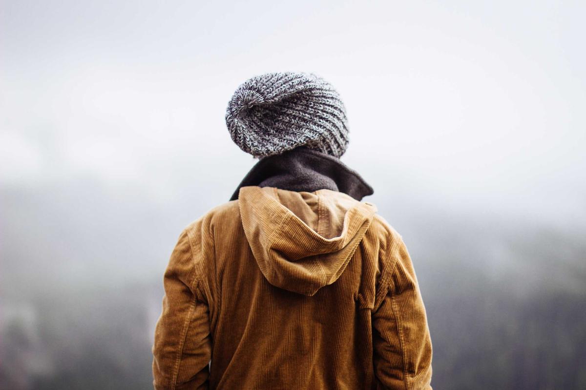 A Guide to Choosing Between Wall Racks and Standing Desk Converters for Your Tiny Home Office Person standing at standing desk converter with laptop and papers, wall rack in background for comparison